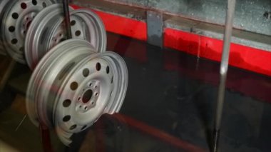 Çelik jantlar otomatik banyoda toz boyama işlemi sırasında düşüyor.