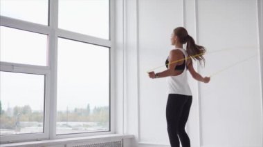 Genç ve atletik bir kadın kasları ısıtır, Bayan hızlı bir şekilde ip üzerinde atlar