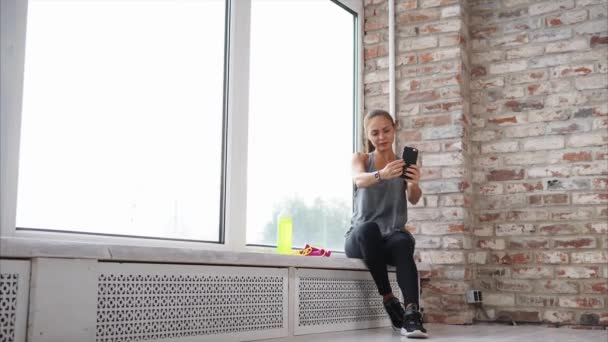 Jeune femme qui pratique le sport, prend des photos d'elle-même sur un téléphone portable — Video