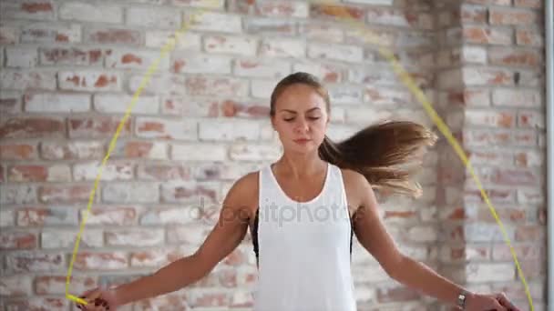 Jeune fille athlétique saute corde en arrière-plan de mur de briques . — Video