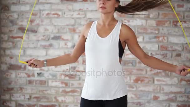 Young woman with slim figure is jumping energetically with rope in gym. — Stock Video