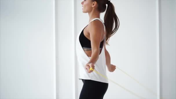 Jeune femme avec tracker de remise en forme à portée de main saute corde dans le club de sport . — Video