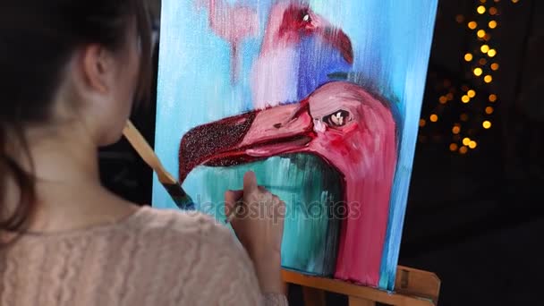 Un joven artista pinta una pintura al óleo con un flamenco — Vídeo de stock