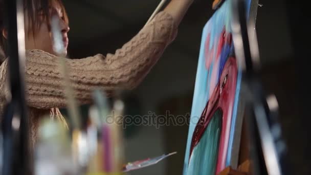 Jonge kunstenaar werkt aan een van haar stukken in studio. — Stockvideo
