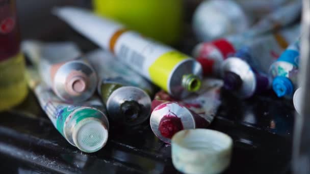 Muitos tubos de metal de corantes acrílicos de cores diferentes estão colocando na oficina de arte . — Vídeo de Stock