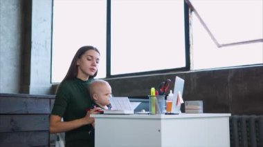 İş kadını çocuğuyla birlikte iş yerinde not alma.