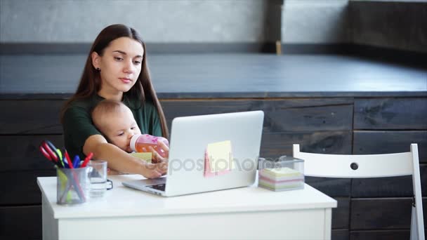Beautiful woman is working in the office with her little kid. — Stock Video