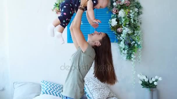 Eine junge Mutter spielt mit ihrer Tochter, sie wirft das Kind hoch, die Mädchen lachen — Stockvideo