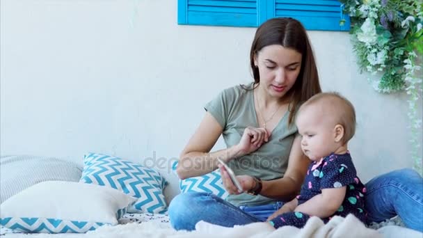 Alegre madre está enseñando a los niños a usar el teléfono inteligente, sentado en el dormitorio — Vídeos de Stock