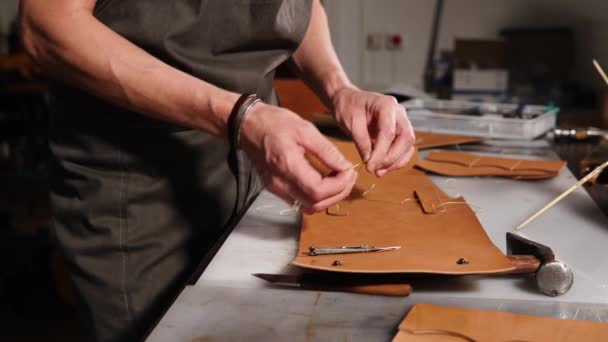 Der Meister näht die Details der Brieftasche mit seinen eigenen Händen, er ist in der Fabrik — Stockvideo