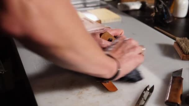 Bliska strzał rąk mistrza, który ociera szmata wykonane przez niego portfel ze skóry — Wideo stockowe