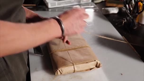 O vendedor da loja empacota as mercadorias em papel artesanal para venda aos compradores — Vídeo de Stock