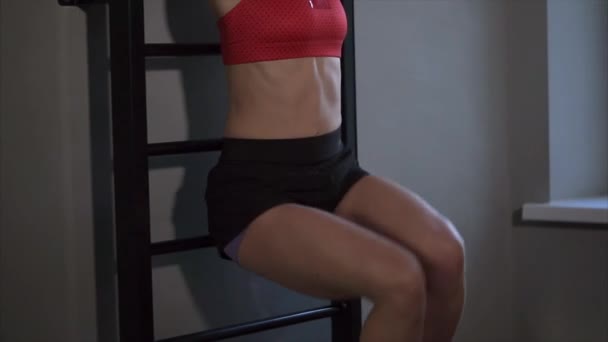 De vrouw versterkt haar pers in de fitnessclub, roept ze haar benen omhoog — Stockvideo