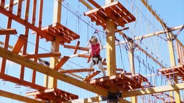 Bir kız bir asılı parkın yürür, o sigorta ile sabitlenir ve cesaretle gider