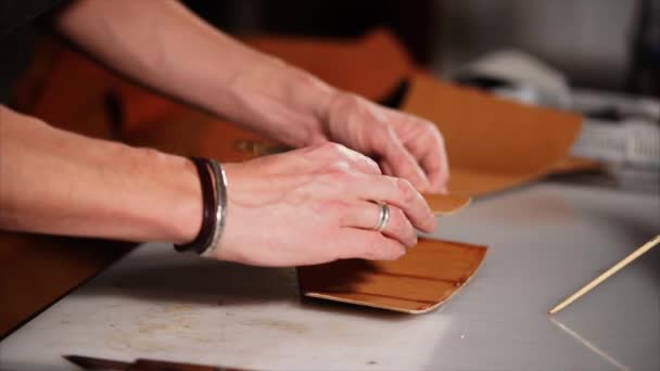 El hombre está pegando dos detalles del producto de cuero, poniendo uno sobre el otro, primer plano — Vídeos de Stock