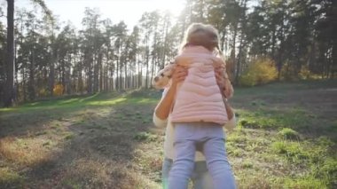 Genç bir anne çocuğunu bir sonbahar Park, orman oynayan kızlar twirling