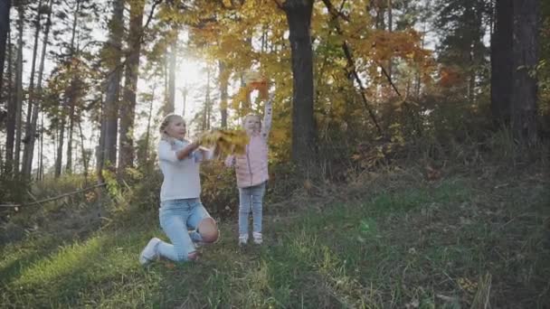 Una donna e sua figlia vomitano foglie mentre camminano in un parco autunnale — Video Stock