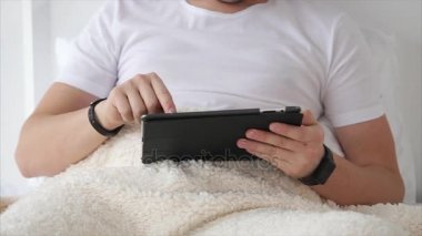 Adam yatakta tablet ile rahatlatıcı.