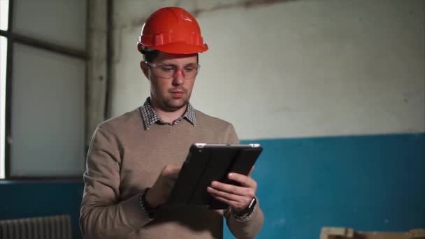 O homem segura uma tábua na mão, na cabeça de um construtor um capacete protetor — Vídeo de Stock