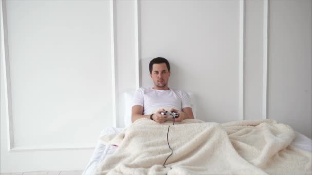 Mann spielt auf Konsole im Bett. — Stockvideo
