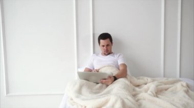 Yetişkin bir adam tutar bir dizüstü bilgisayar ve taşınabilir bir gadget Haberler raporlar izler