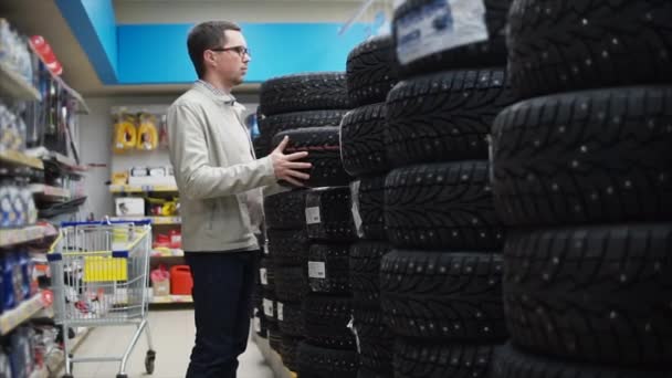 Мужчина выбирает зимние шины в автосалоне — стоковое видео