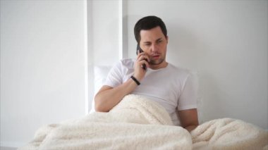 Yatakta yatarken konuşmak bir telefon olan adam