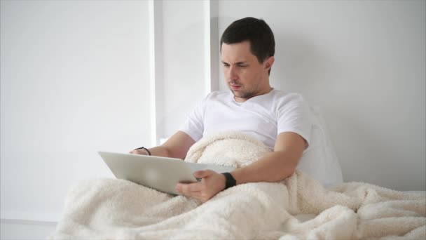 Adam yatakta yatarken dizüstü bilgisayarda Web tarama — Stok video