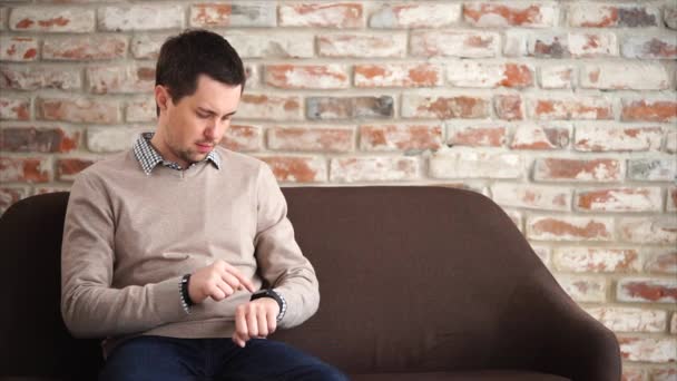 Hombre usando reloj inteligente cuando espera en el vestíbulo — Vídeos de Stock