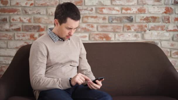 Hombre pasar tiempo con el teléfono celular cuando espera en el vestíbulo — Vídeos de Stock