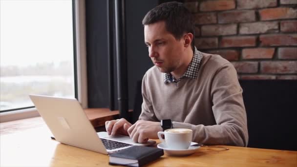 Человек, работающий с ноутбуком в кафе — стоковое видео