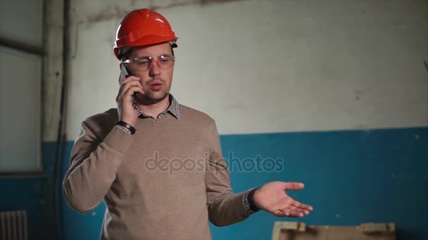 Annoyed engineer talking on mobile phone at work — Stock Video