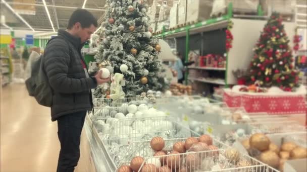 Ο άνθρωπος που αγοράζοντας διακοσμήσεις χριστουγεννιάτικων δέντρων στο κατάστημα — Αρχείο Βίντεο