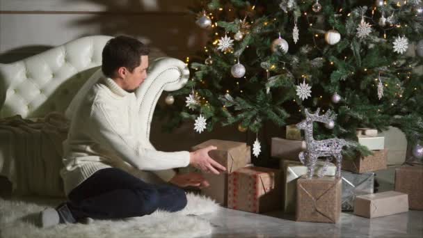 Człowiek, kładzenie świąteczne prezenty pod drzewem — Wideo stockowe