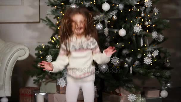Αξιολάτρευτο κοριτσάκι άλμα ευτυχώς κοντά το χριστουγεννιάτικο δέντρο. — Αρχείο Βίντεο