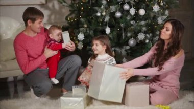 Genç kadın eşi, kızı ve bebek oğluna Noel hediyeleri veriyor.