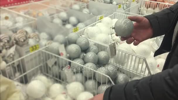 Mans mãos estão tocando bolas para decorar Natal e árvores de ano novo em uma loja — Vídeo de Stock