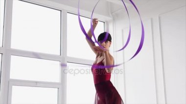 Güzel kadın jimnastikçi bir kurdele ile pratik.