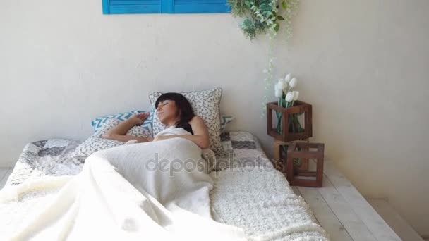 Молодая женщина спит на подушке в своей кровати в спальне — стоковое видео