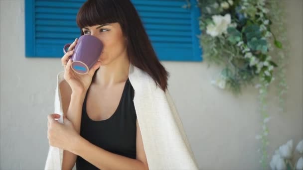 Jeune brune assise sur une terrasse le matin et buvant du café — Video