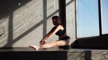 Genç kadın bir spor salonunda fitness silindir üzerinde oturan ve egzersizleri yapıyor