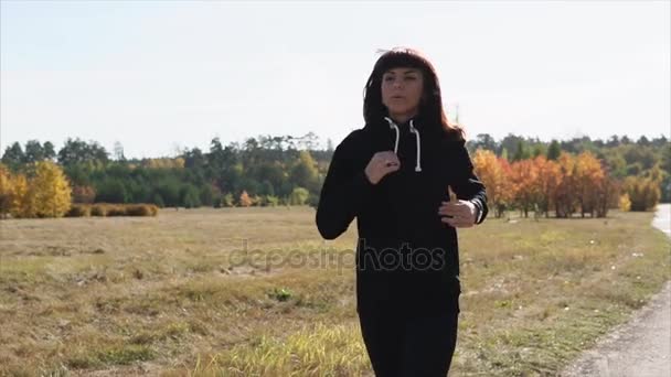 Uma mulher correndo no parque, a senhora está correndo ativamente através do parque — Vídeo de Stock