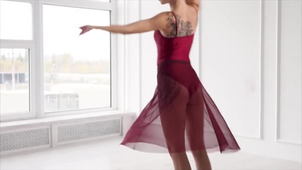 Jeune femme mince tourbillonne dans une danse dans un hall près de grandes fenêtres — Video