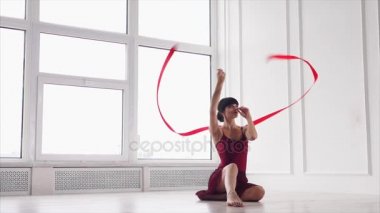 bir kurdele ile uğraşan bir sporcumuz yerde oturur ve germe yok