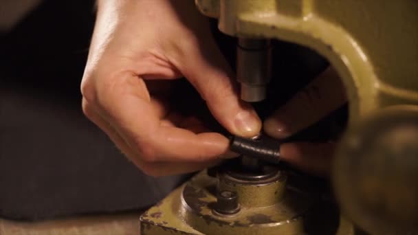 Close up shot of a mans hands, who makes a hole in a piece of leather for decor — Stock Video