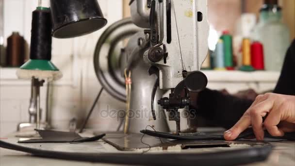 Close up shot of a mechanical sewing machine a man sews parts of a leather piece — Stock Video