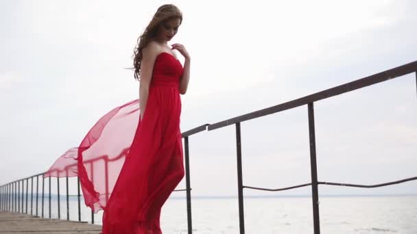 Mooie vrouw met een jurk tegoed in de buurt van de zee, ze ziet er nadenkend en romantisch — Stockvideo