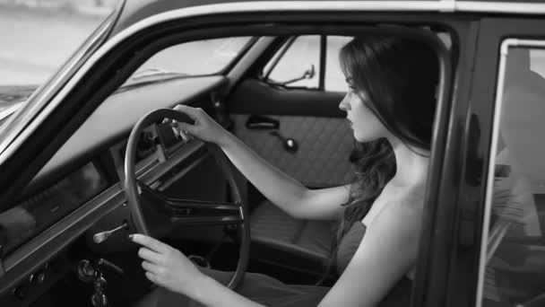 A woman sits behind the wheel of a vehicle is similar to a retro movie character — Stock Video