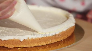 Kadın bir krem ile bir kek üzerine çizer.