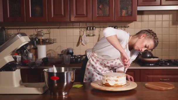 Woman applies cream on the cake — Stock Video